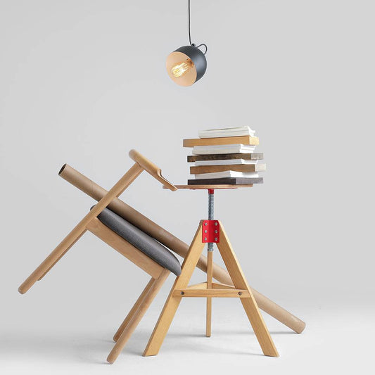 Lampadario nero con diffusore rotondo e cavo nero, illuminazione moderna e di design, posizionato sopra una pila di libri e oggetti di arredo