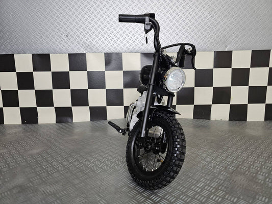 Vista frontale della moto elettrica per bambini modello chopper nero, con manubrio alto e grande faro rotondo, sedile in pelle e dettagli in stile motociclista.