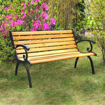 Panca in ghisa e legno Real posizionata in giardino tra fiori e piante. Misura 126 x 60 x 77 cm, perfetta per arredare spazi verdi.