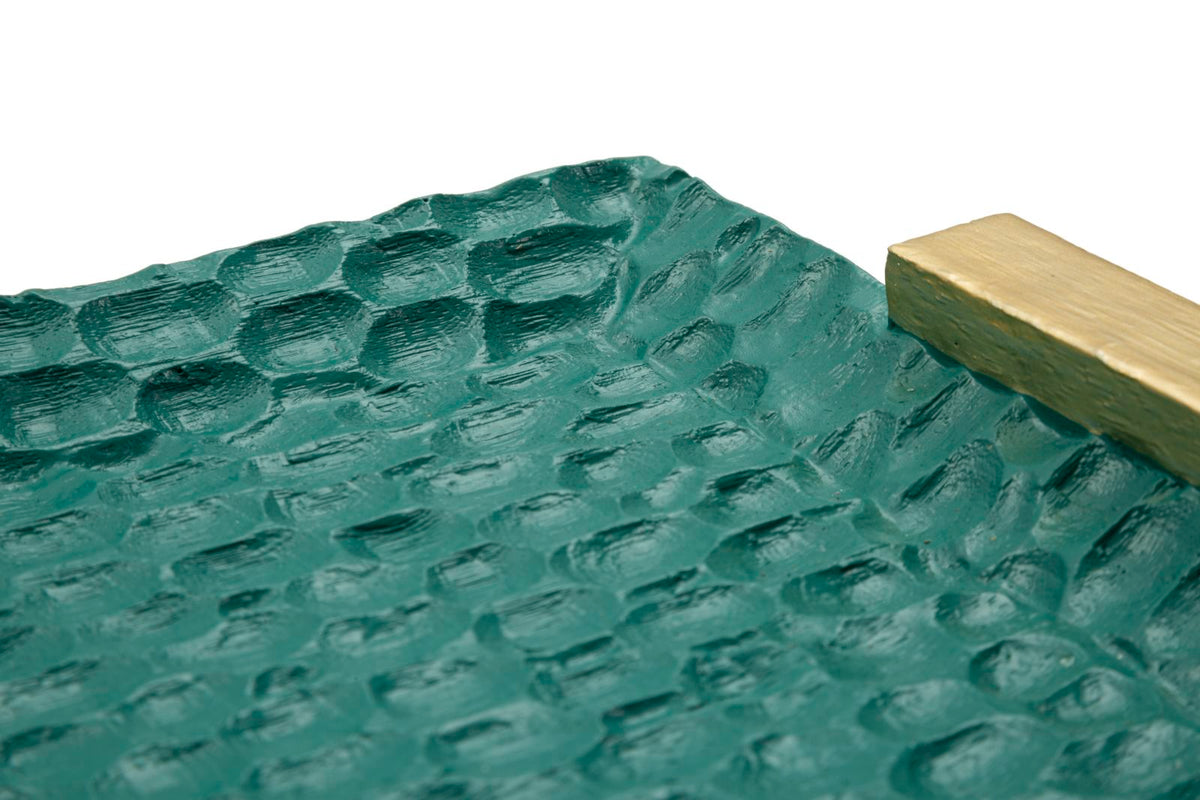 Dettaglio angolo svuotatasche Grent con texture martellata verde e manico dorato, design sofisticato per interni di classe.