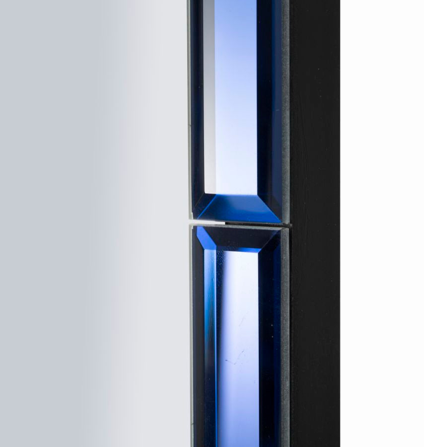 Primo piano della cornice blu sfaccettata dello specchio da parete Berlino, design moderno e luminoso per interni sofisticati.