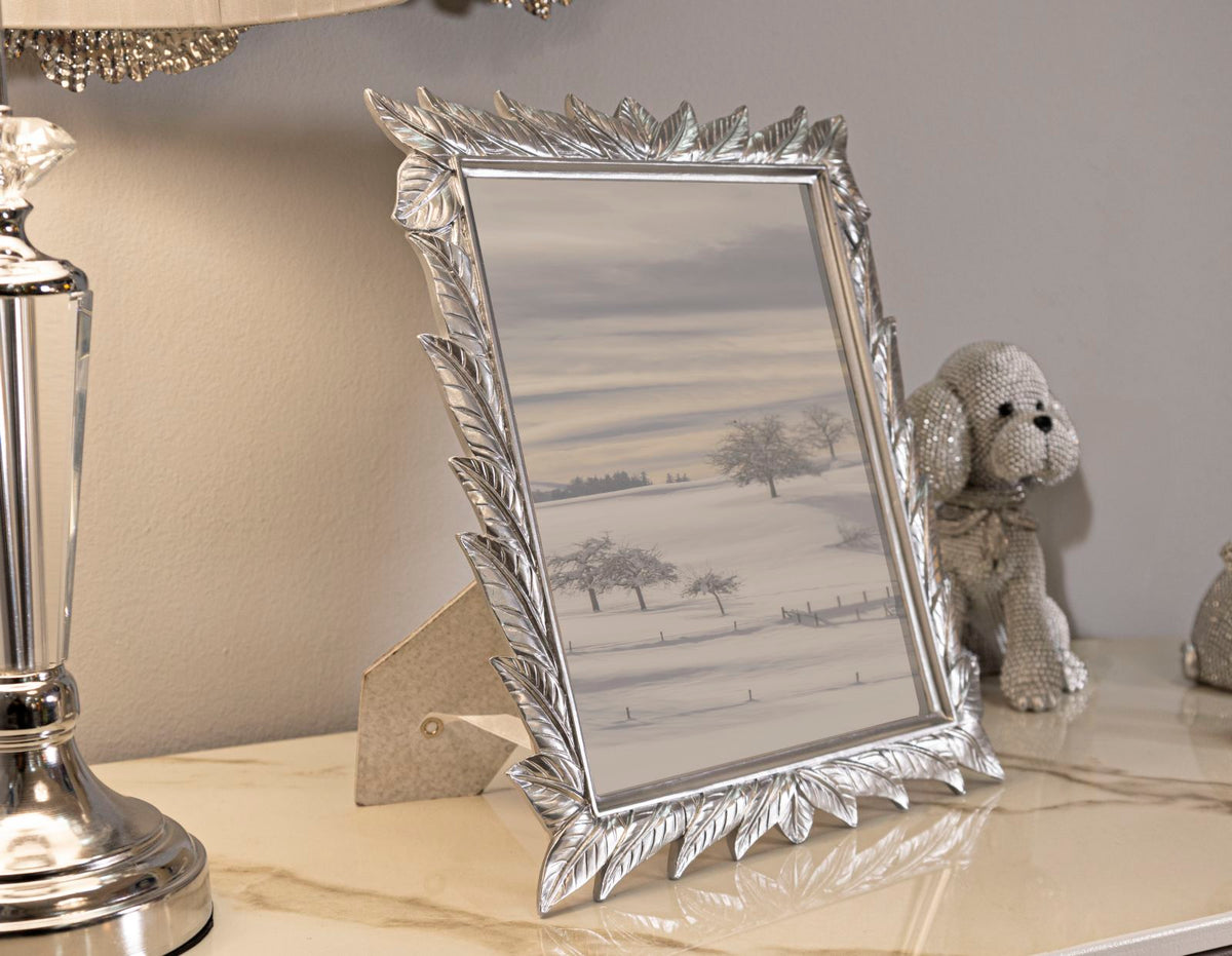 Cornice Leavy Silver 27X2X32,3 cm su mobile, con foto paesaggio invernale, stile decorativo con foglie argentate, misura interna 20X25 cm.