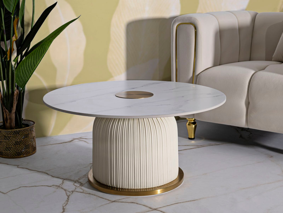 Tavolino Nova con top effetto marmo e base dorata in un soggiorno elegante, abbinato a divano bianco e piante decorative.