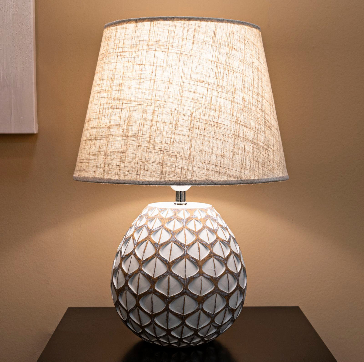 Lampada da tavolo Tibet accesa su mobile scuro, Ø 35X52 cm, design elegante con paralume in tessuto e base decorativa.