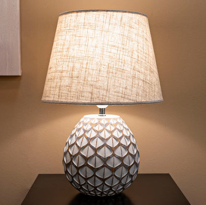 Lampada da tavolo Tibet accesa su mobile scuro, Ø 35X52 cm, design elegante con paralume in tessuto e base decorativa.