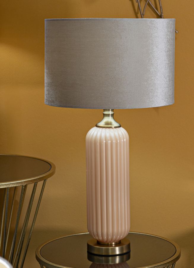 Lampada da tavolo Perly -C- posizionata su tavolino in salotto, design elegante con paralume beige e base in vetro color pesca.