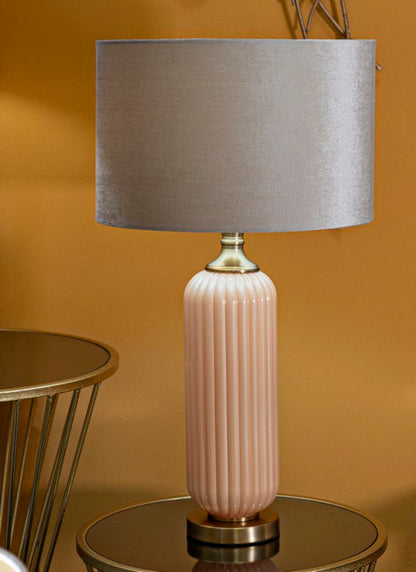 Lampada da tavolo Perly -C- posizionata su tavolino in salotto, design elegante con paralume beige e base in vetro color pesca.