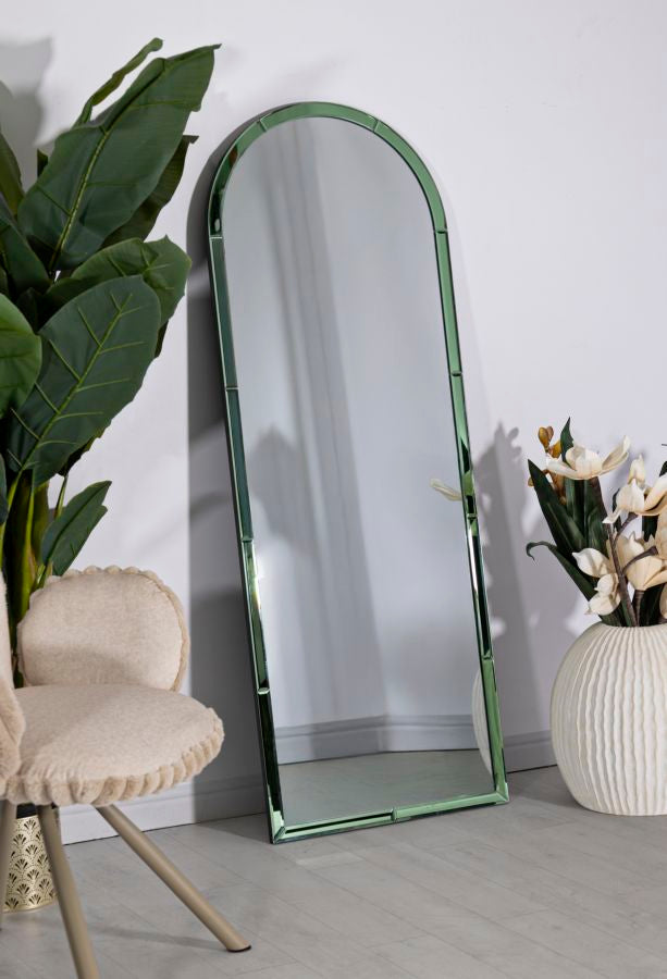 Specchio Baku verde posizionato a terra in un ambiente moderno, ideale per ampliare visivamente lo spazio con eleganza.