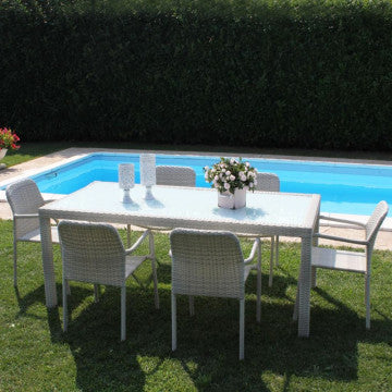 Set da giardino con tavolo Azore grigio e sedie coordinate, posizionato su prato vicino a una piscina, ideale per cene all'aperto.