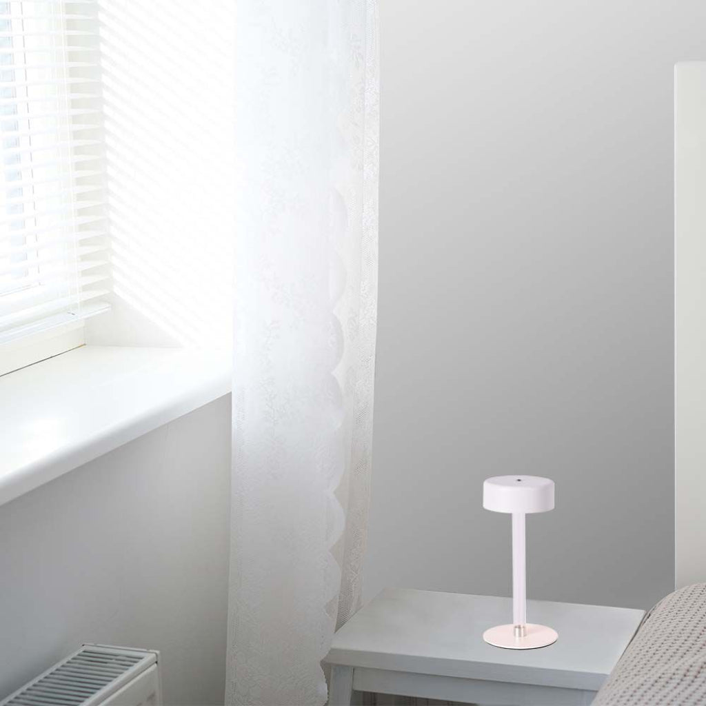 Lampada da tavolo V-Tac LED 3W bianca posizionata su un comodino vicino a una finestra, perfetta per illuminazione ambientale in camera da letto.