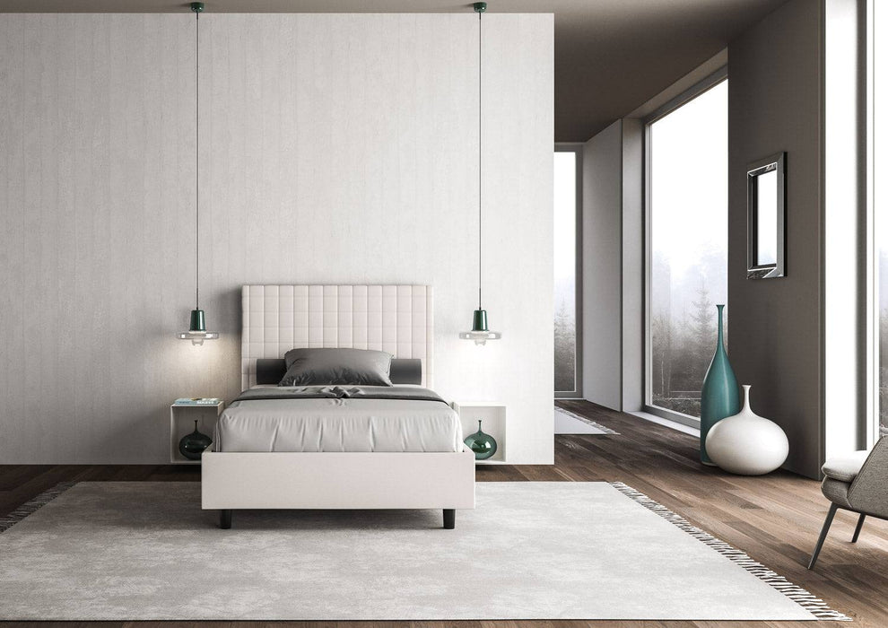 Letto singolo contenitore imbottito similpelle Sunny bianco in ambiente raffinato con tappeto chiaro e decorazioni minimaliste.