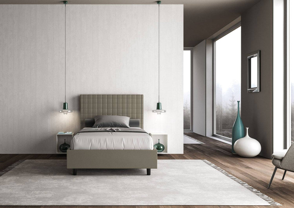 Letto singolo contenitore imbottito similpelle Sunny grigio tortora in ambiente elegante con ampie finestre e arredamento minimalista.