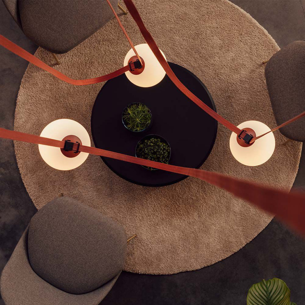 Illuminazione da soffitto con lampade LED sferiche opali, sospese con cavi arancioni, in ambiente living moderno e accogliente