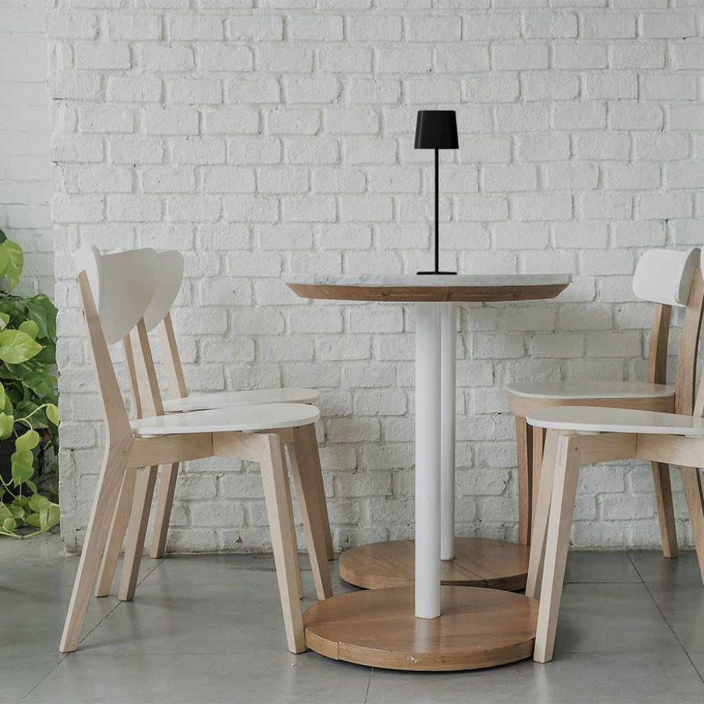 Lampada da tavolo nera in ambiente esterno, illuminando un tavolo con tazza di tè e ciotola di legno, perfetta per uso interno ed esterno