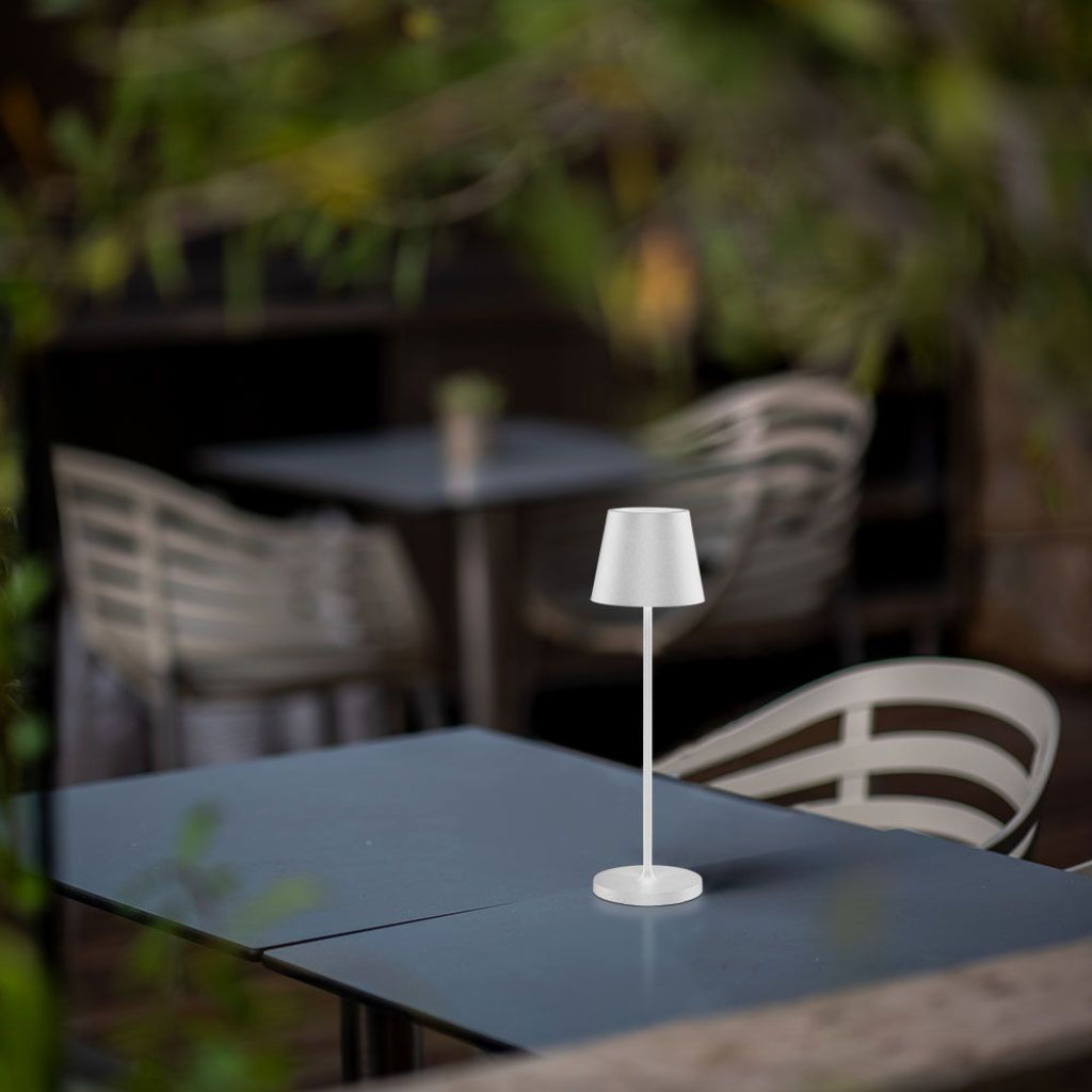Lampada LED da tavolo bianca con ricarica wireless e protezione IP54, ideale per ambienti esterni come terrazze o giardini.