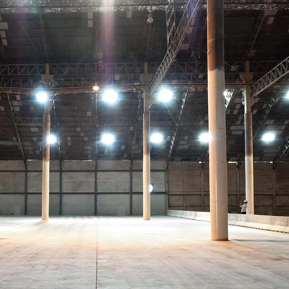 Campane LED UFO 100W CCT 3in1 IP65 con Interruttore installate in un magazzino industriale, illuminazione potente e uniforme.