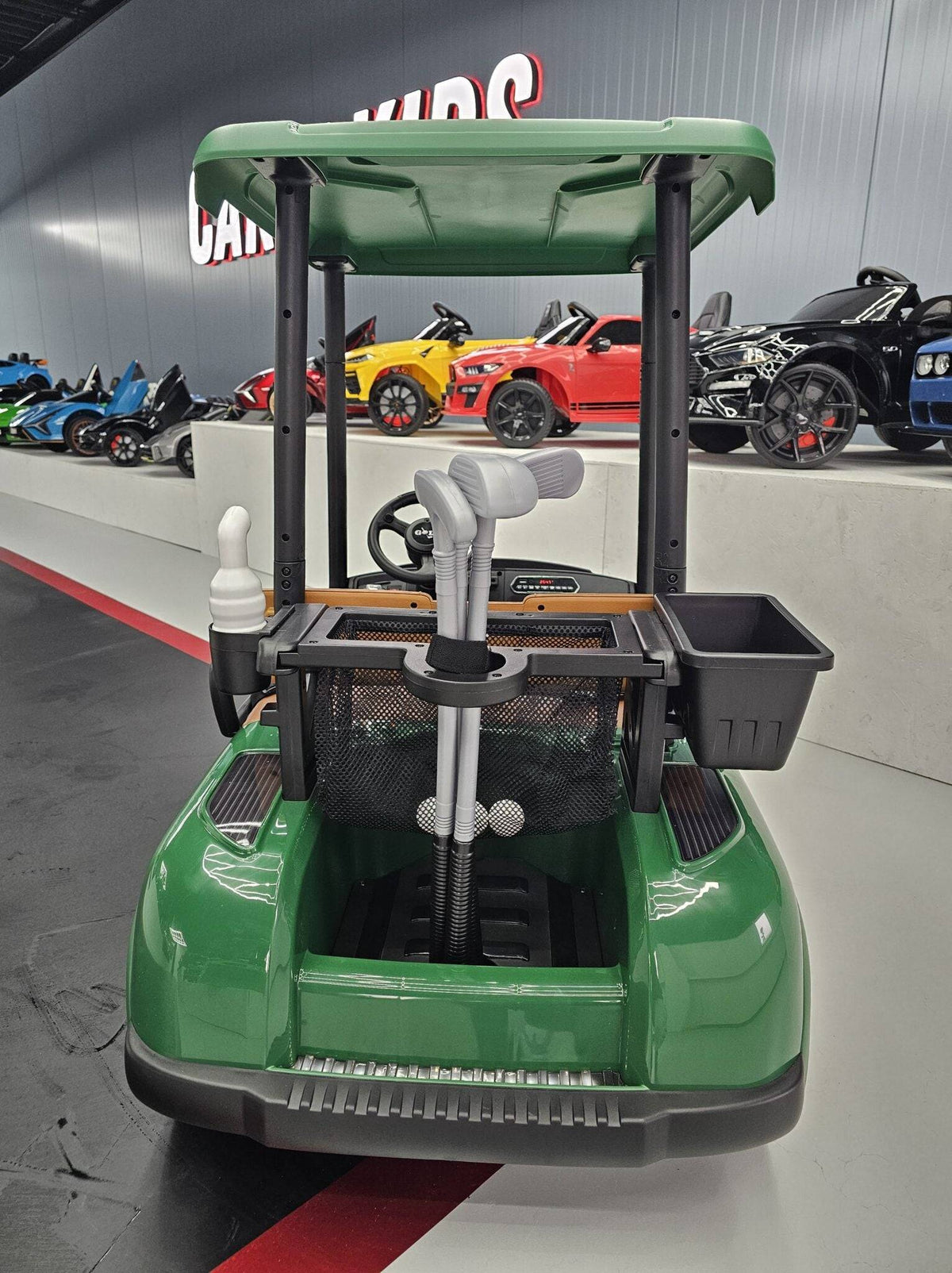 Vista laterale del carrello da golf elettrico per bambini verde con ruote robuste e dettagli in plastica nera, ideale per giochi all'aperto