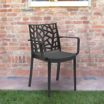 Poltrona Matrix antracite in polipropilene posizionata in giardino, perfetta per ambienti outdoor grazie alla struttura resistente e impilabile.