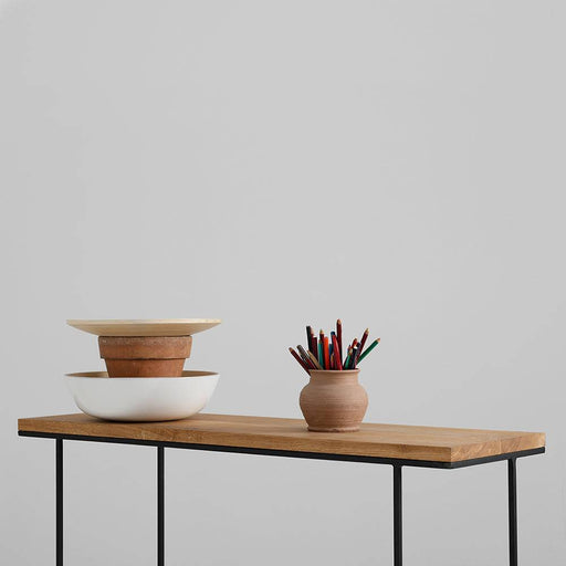 Dettaglio della superficie in legno di quercia naturale con bordo smussato, supportata da struttura in metallo nero, stile moderno
