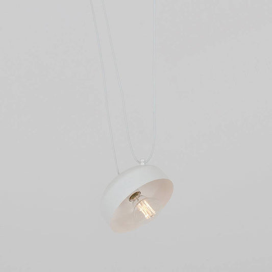 Lampadario bianco sospeso con design industriale, forma rotonda, lampadina a vista, abbinato a parete bianca e arredi moderni
