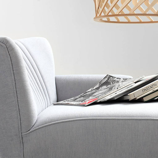 Dettaglio di una chaise longue HARRY P in tessuto bianco con schiena imbottita e braccioli, decorata con riviste, stile moderno e minimalista.