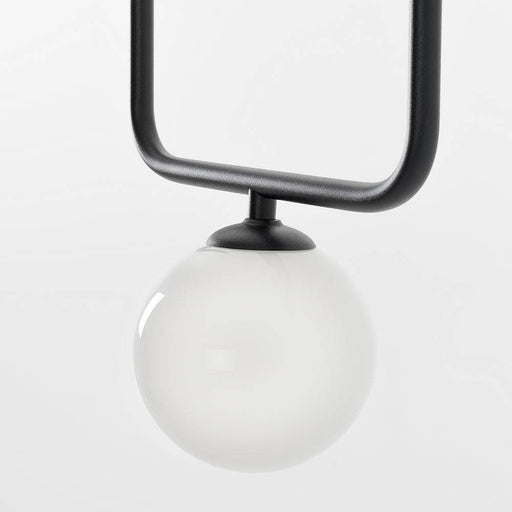 Dettaglio della lampada a soffitto con sfera in vetro bianco e supporto nero, focus sulla base e design contemporaneo