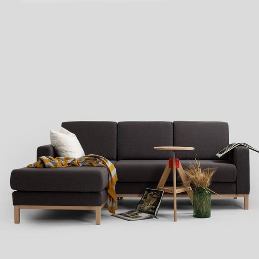 Divano in tessuto nero con struttura in legno chiaro, configurazione angolare, stile minimalista e funzionale per ambienti moderni.