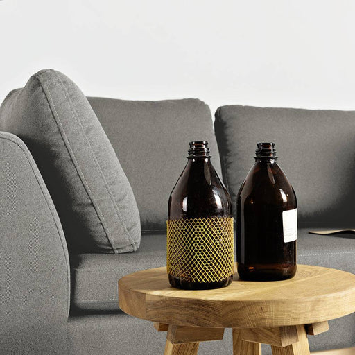 Dettaglio di divano grigio con cuscini in tessuto, struttura in legno chiaro, stile contemporaneo e atmosfera accogliente in soggiorno