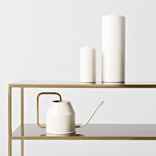 Dettaglio di console con accessori in ceramica bianca e vasi decorativi, superficie in vetro e struttura in metallo dorato.
