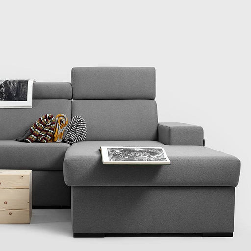 Divano angolare in tessuto grigio scuro con seduta spaziosa, braccioli larghi e stile minimalista, perfetto per ambienti moderni.