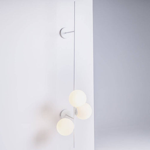Dettaglio dell'applique BOBLER 2connect bianco con sfere di vetro opaco, installata su parete bianca, stile minimalista e funzionale