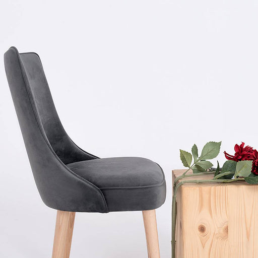 Vista frontale della sedia Kiko grigio lilla con seduta imbottita e schienale in velluto grigio scuro, supporto in legno naturale