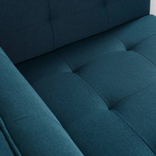 Dettaglio del divano in tessuto blu con cuciture a quadrati, seduta confortevole e imbottita, perfetto per ambienti contemporanei.