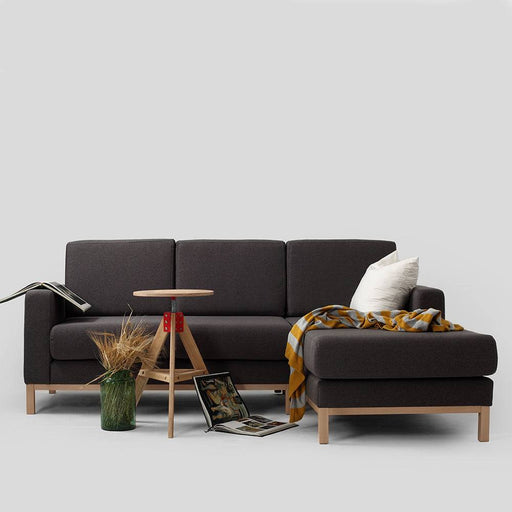 Divano angolare in tessuto nero con struttura in legno chiaro, stile minimalista e confortevole, perfetto per ottimizzare gli spazi
