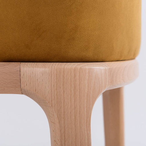 Dettaglio della base in legno naturale della sedia LULU con braccioli, rivestimento in velluto senape, stile vintage e comfort elevato