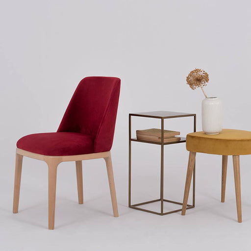 Sedia in velluto rosso con struttura in legno naturale, inseribile in soggiorni o sale da pranzo dallo stile contemporaneo.