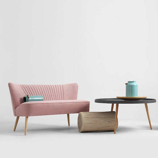 Divano con rivestimento rosa in velluto con schiena imbottita e gambe in legno chiaro, stile vintage e comfort moderno, arredo elegante