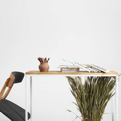 Immagine di una scrivania con piano in rovere e struttura in metallo bianco, decorata con vasi e libri in stile minimalista