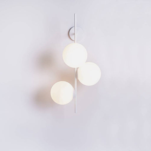 Applique BOBLER bianca con tre sfere di vetro opalino, montata su parete con supporto minimalista, luce diffusa e stile contemporaneo