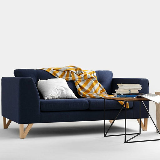 Divano blu scuro con gambe in legno naturale, seduta e schienale imbottiti, stile minimalista, ideale per soggiorno contemporaneo.