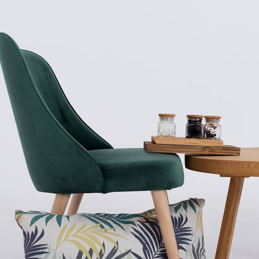Dettaglio della poltrona verde in velluto con schienale curvato, seduta imbottita e gambe in legno naturale, perfetta per ambienti eleganti.