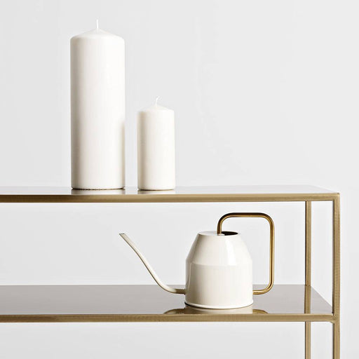 Decorazione con due grandi candele bianche e una teiera bianca con manico dorato su console Senso Flower Metal, stile minimalista e raffinato