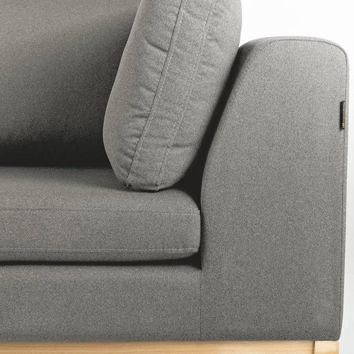 Dettaglio del divano 3 posti in tessuto grigio chiaro con cuscini coordinati, primo piano, struttura in legno naturale, design minimalista