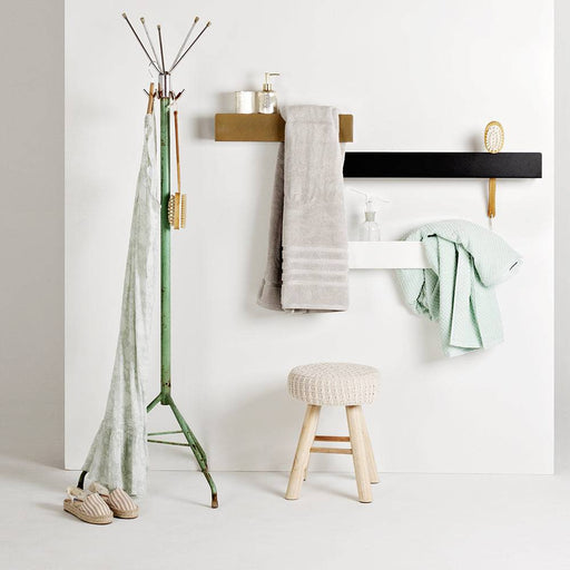 Immagine di scaffale bianco con supporto a parete, decorato con asciugamani e accessori bagno, stile moderno e funzionale
