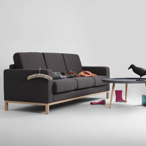 Dettaglio del divano Scandic in tessuto grigio scuro con braccioli imbottiti e struttura in legno naturale, stile minimalista.