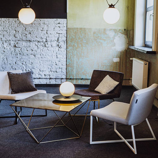 Ambientazione con poltrona pied de poule chiaro in stile moderno, con lampade a soffitto e pareti in pietra, atmosfera accogliente