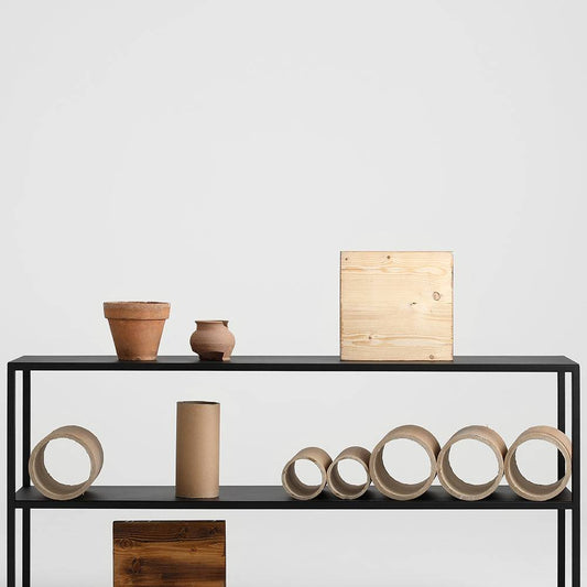 Libreria in metallo nero con tre ripiani, decorata con vasi di terracotta e oggetti di ceramica, stile scandinavo e design funzionale