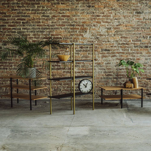 Scaffale in stile industriale con ripiani in legno di rovere e struttura in metallo dorato, decorato con piante e oggetti di design.