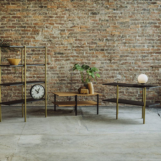 Immagine di una consolle moderna con struttura in nero e dettagli in oro, inserita in ambiente con parete in mattoni a vista, stile industriale.