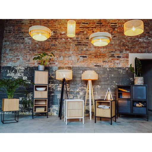 Interno di un ambiente con scaffali in legno chiaro e struttura in metallo nero, illuminato da lampade da terra, stile industriale